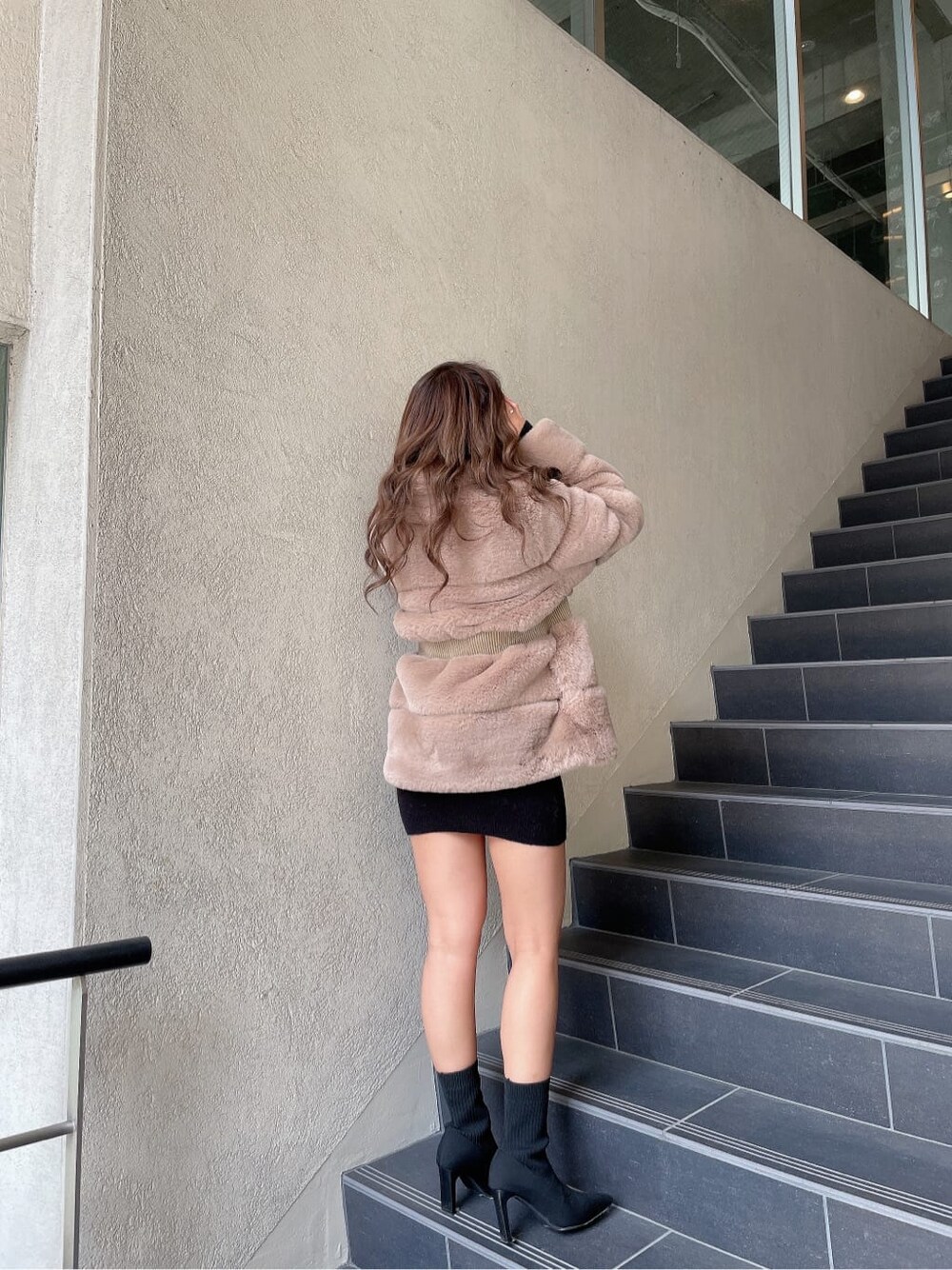 ブラック系のブーツ、ベージュ系のその他アウター、ブラック系のワンピースを着用したレディースの冬コーディネートの2枚目の写真