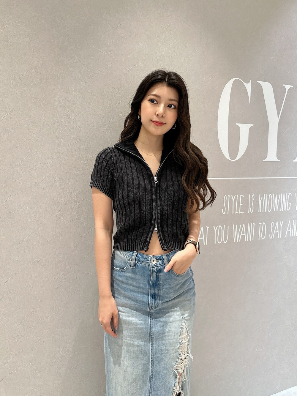 ブルー系のデニムスカート、ホワイト系のサンダル、ブラック系のニット/セーターを着用したレディースの夏コーディネートの6枚目の写真