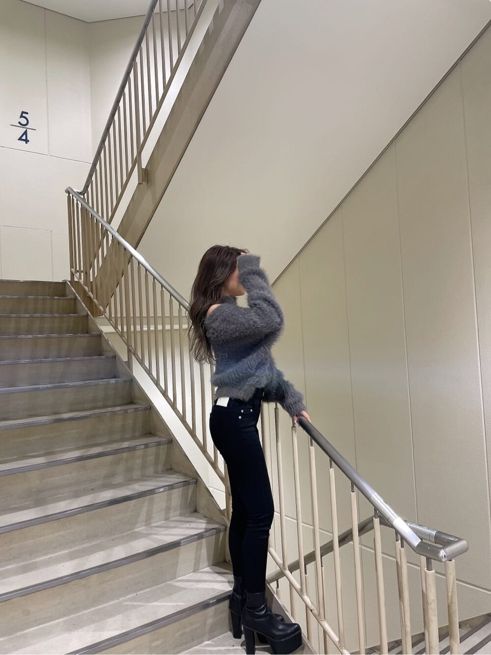 グレー系のニット/セーター、ブラック系のブーツ、ブラック系のチューブトップを着用したレディースの秋コーディネートの4枚目の写真