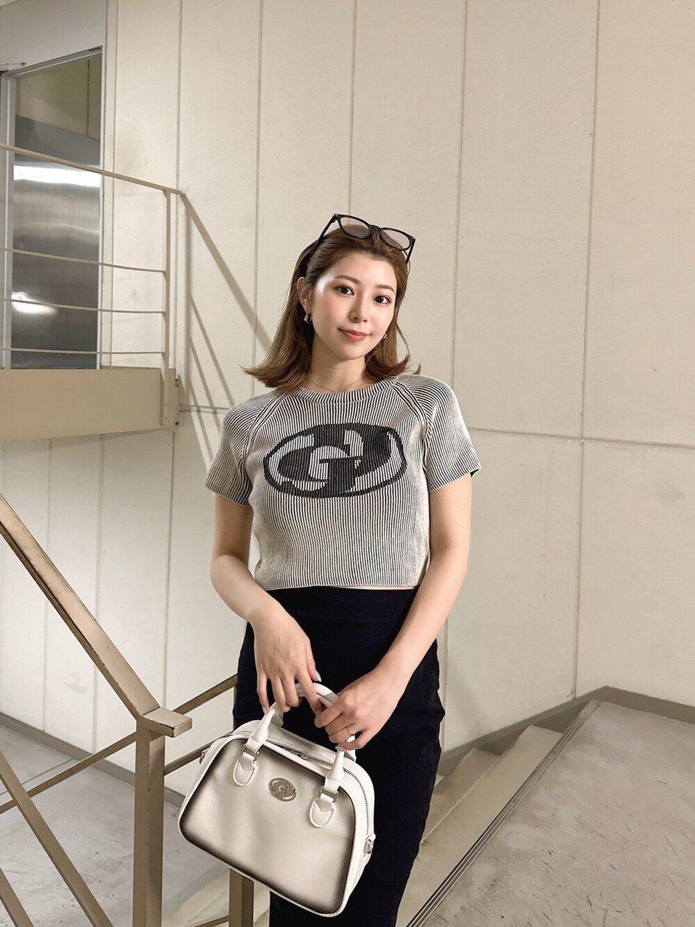 ホワイト系のニット/セーター、ホワイト系のハンドバッグを着用したレディースの夏コーディネートの3枚目の写真