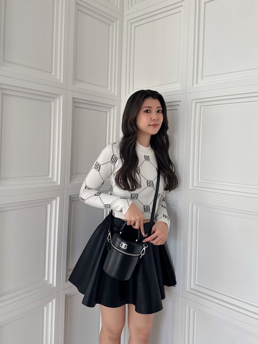 ブラック系のスカート、ブラック系のハンドバッグ、ホワイト系のニット/セーターを着用したレディースの冬コーディネートの6枚目の写真