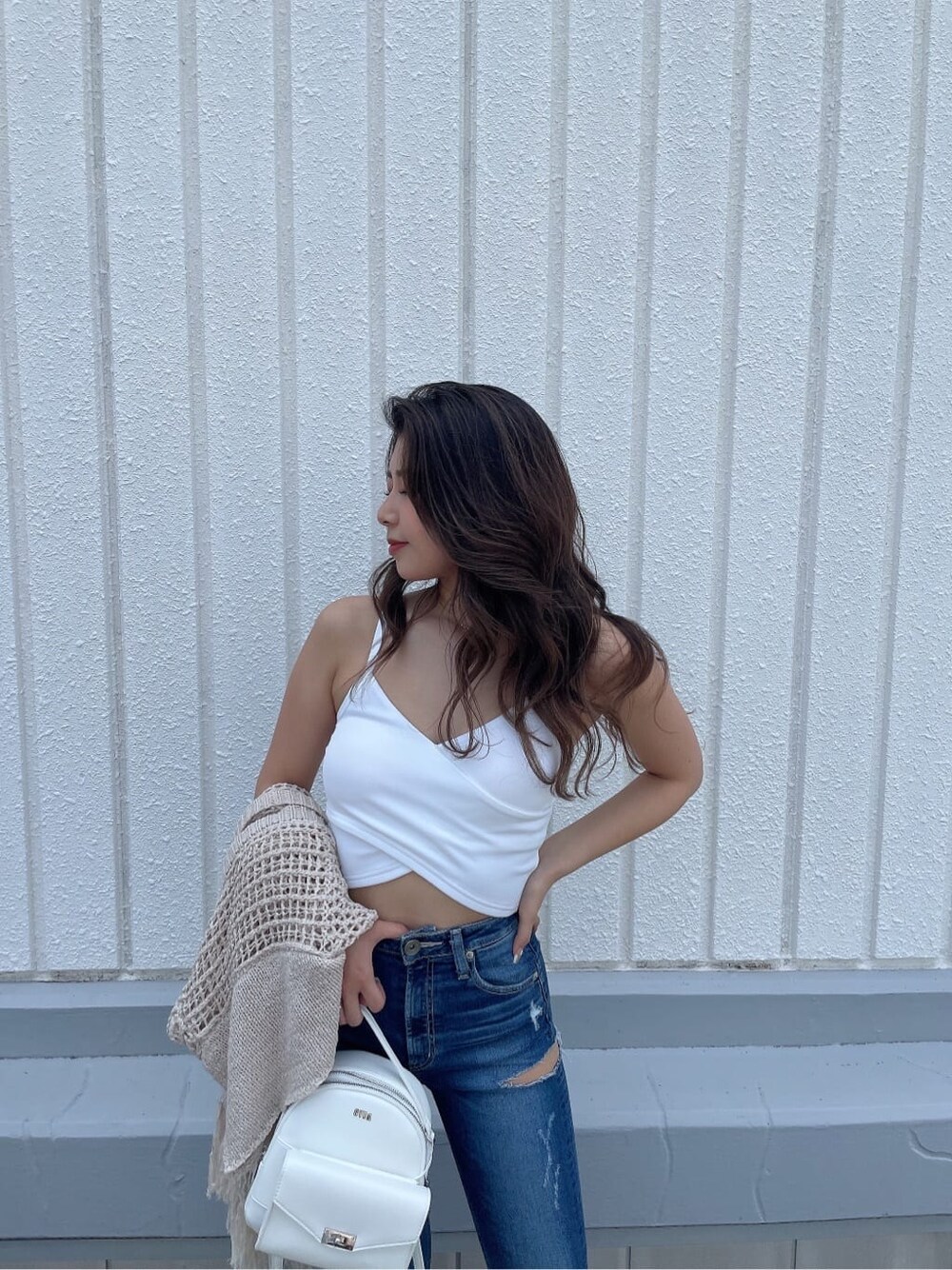 ホワイト系のサンダル、ブルー系のデニムパンツ、ホワイト系のハンドバッグを着用したレディースの夏コーディネートの6枚目の写真