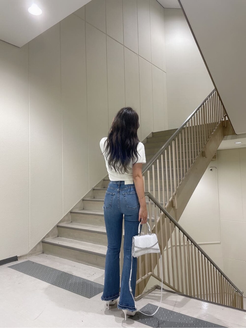 ホワイト系のニット/セーター、ホワイト系のハンドバッグ、ホワイト系のパンプスを着用したレディースの夏コーディネートの3枚目の写真