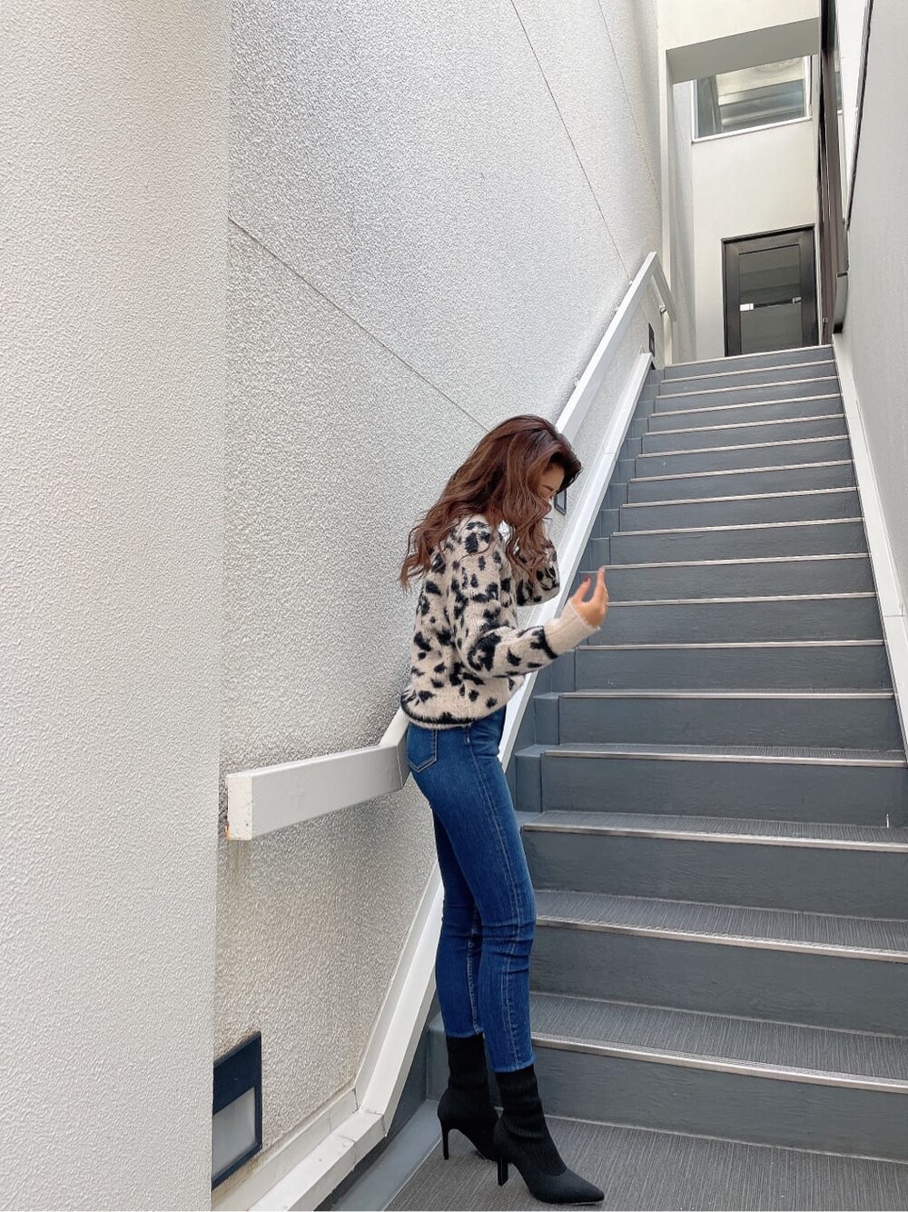 ホワイト系のニット/セーター、ブルー系のデニムパンツ、ブラック系のブーツを着用したレディースの秋コーディネートの4枚目の写真