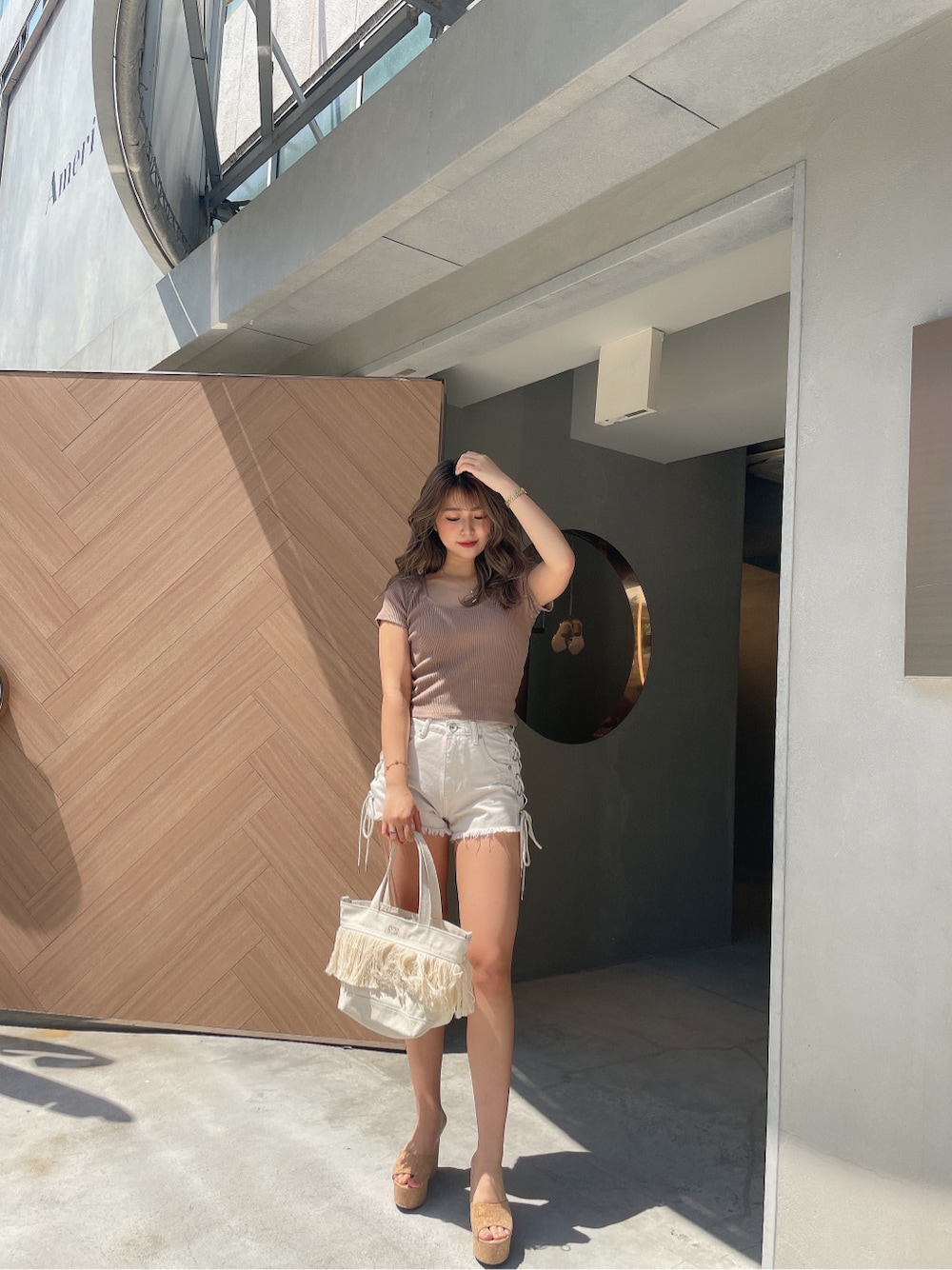 ベージュ系のサンダル、ホワイト系のハンドバッグ、ホワイト系のデニムパンツを着用したレディースの春コーディネートの3枚目の写真