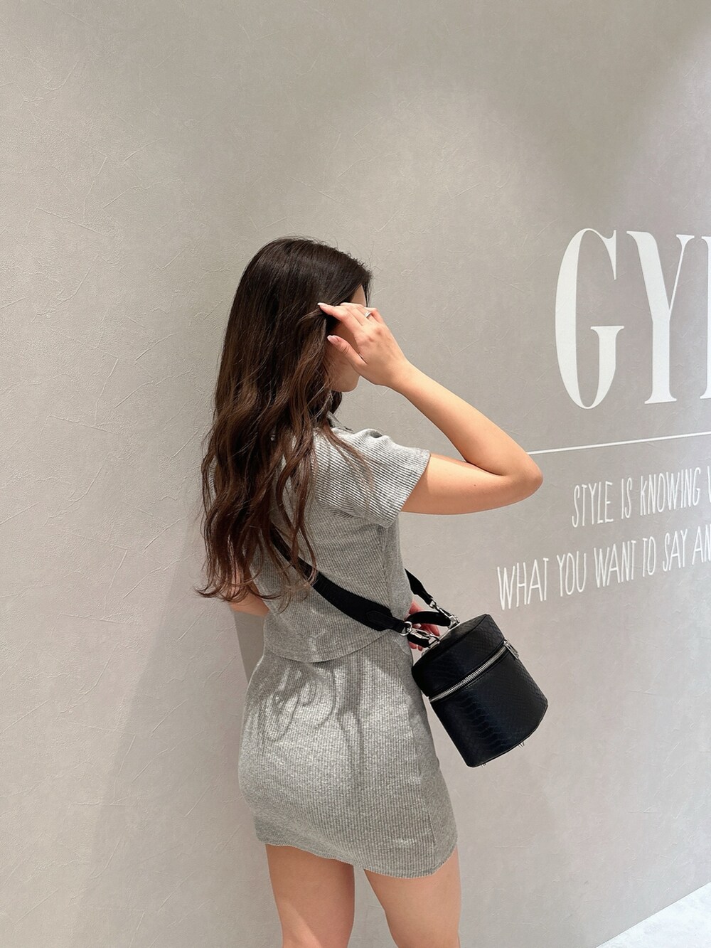 グレー系のワンピース、ブラック系のハンドバッグ、ブラック系のブーツを着用したレディースの春コーディネートの7枚目の写真