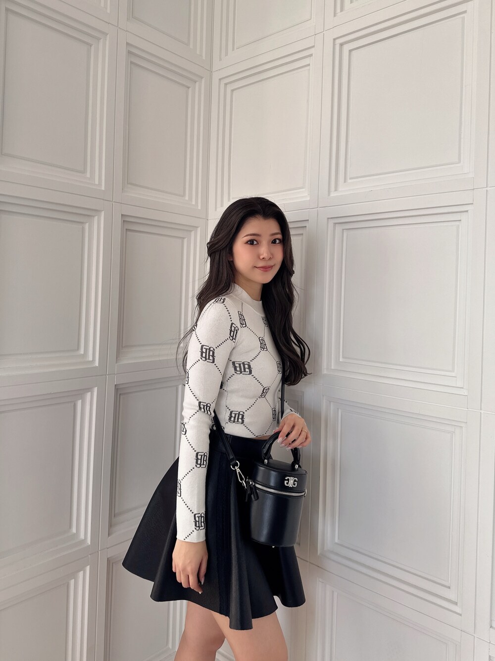 ブラック系のスカート、ブラック系のハンドバッグ、ホワイト系のニット/セーターを着用したレディースの冬コーディネートの7枚目の写真