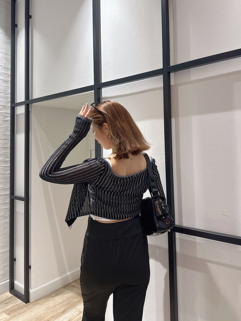 ブラック系のハンドバッグ、ブラック系のカーディガン/ボレロ、ホワイト系のキャミソールを着用したレディースの夏コーディネートの2枚目の写真