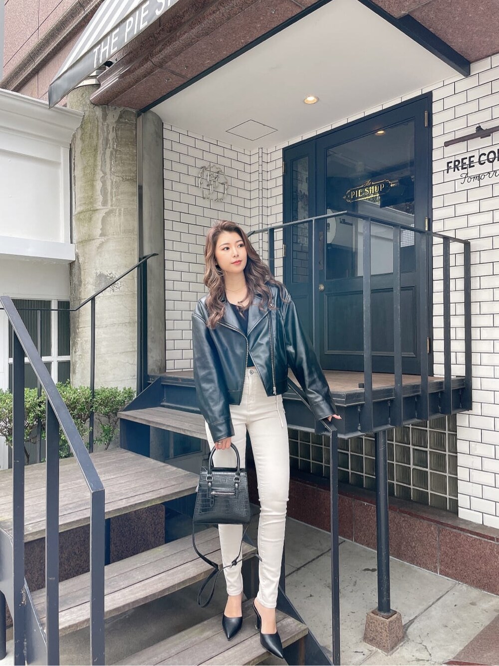 ブラック系のハンドバッグ、ブラック系のパンプス、ブラック系のライダースジャケットを着用したレディースの冬コーディネートの3枚目の写真