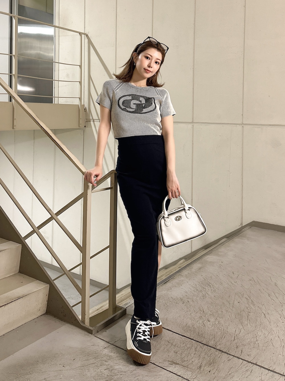 ホワイト系のニット/セーター、ホワイト系のハンドバッグを着用したレディースの夏コーディネートの2枚目の写真