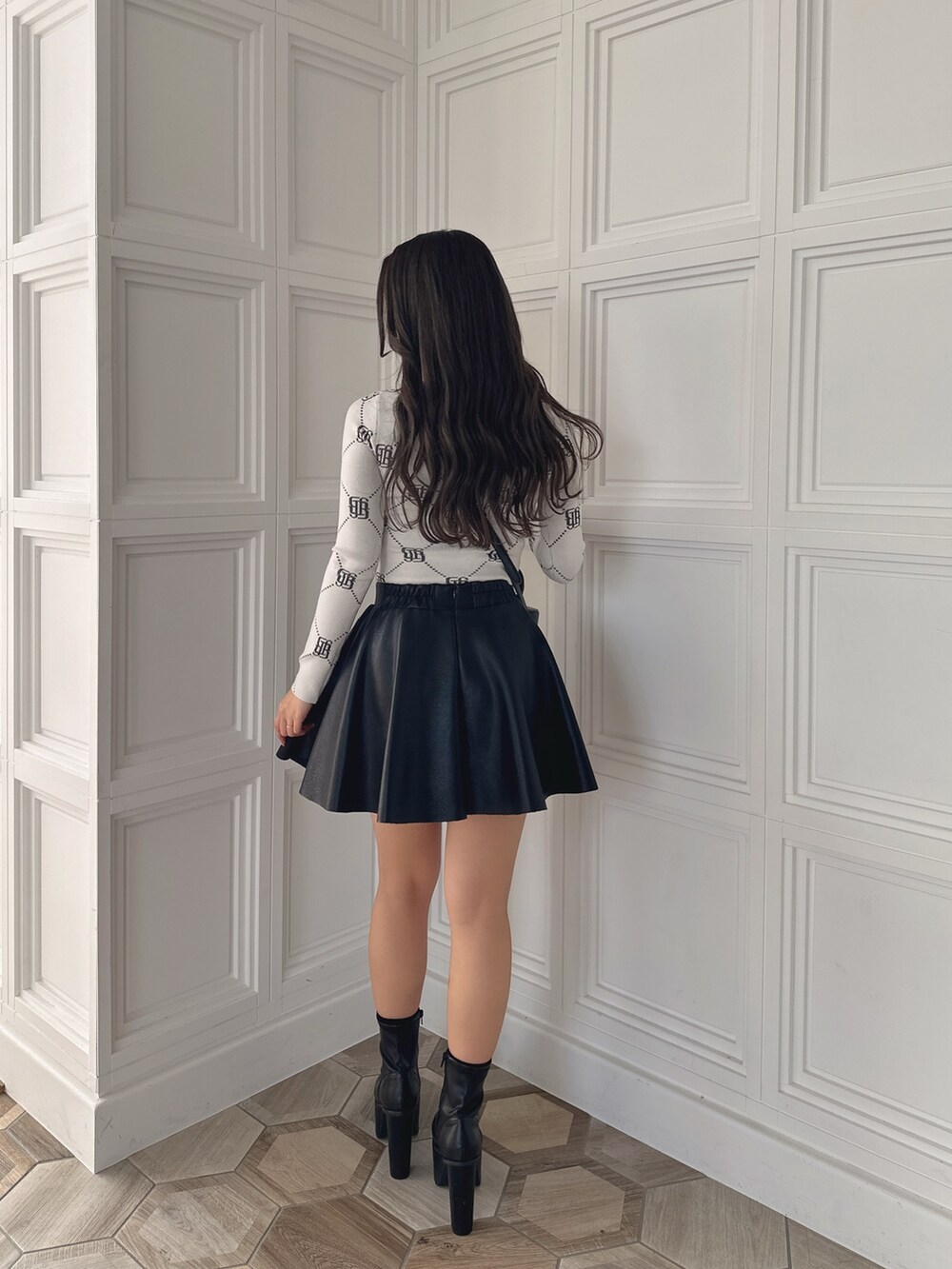 ブラック系のスカート、ブラック系のハンドバッグ、ホワイト系のニット/セーターを着用したレディースの冬コーディネートの4枚目の写真