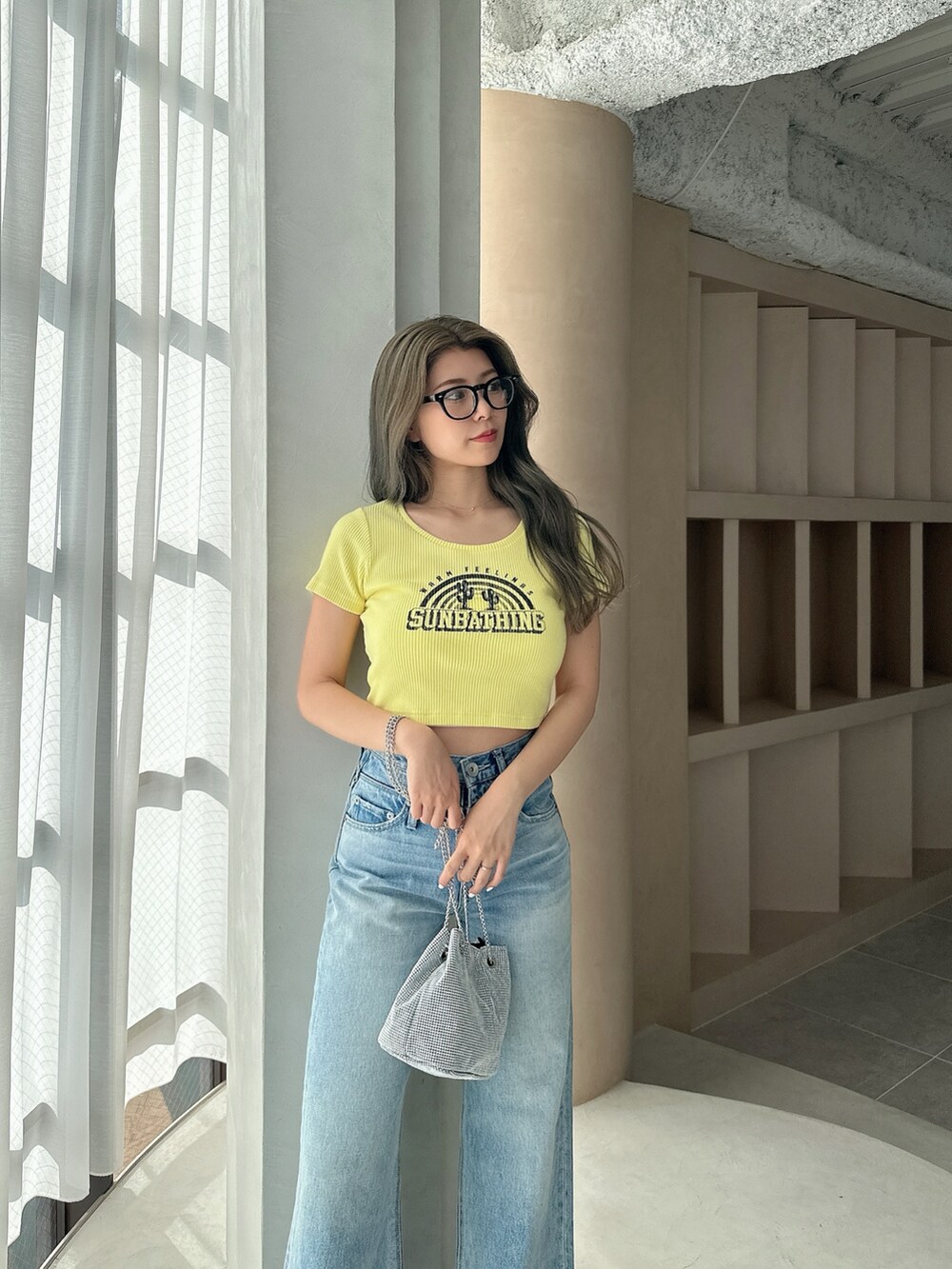 イエロー系のTシャツ/カットソー、シルバー系のショルダーバッグ、ブルー系のデニムパンツを着用したレディースの夏コーディネートの4枚目の写真