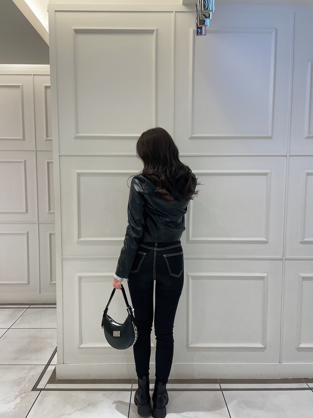 グレー系のTシャツ/カットソー、ブラック系のライダースジャケット、ブラック系のハンドバッグを着用したレディースの冬コーディネートの2枚目の写真