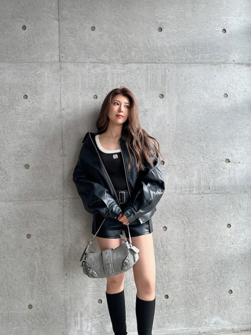 グリーン系のショルダーバッグ、ブラック系のブーツ、ブラック系のニット/セーターを着用したレディースの秋コーディネートの5枚目の写真