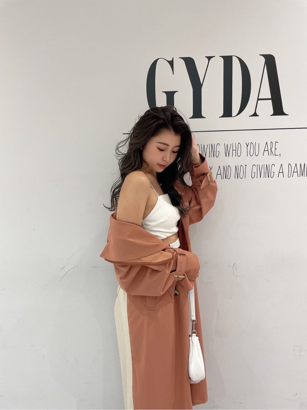 ホワイト系のキャミソール、ホワイト系のパンプス、オレンジ系のトレンチコートを着用したレディースの春コーディネートの5枚目の写真