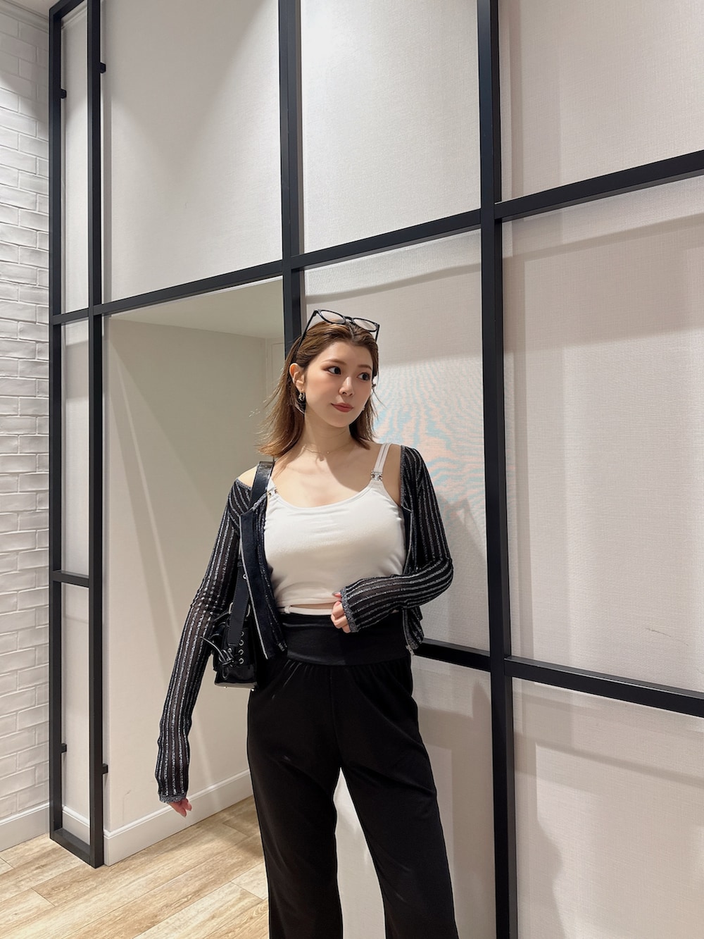 ブラック系のハンドバッグ、ブラック系のカーディガン/ボレロ、ホワイト系のキャミソールを着用したレディースの夏コーディネートの3枚目の写真