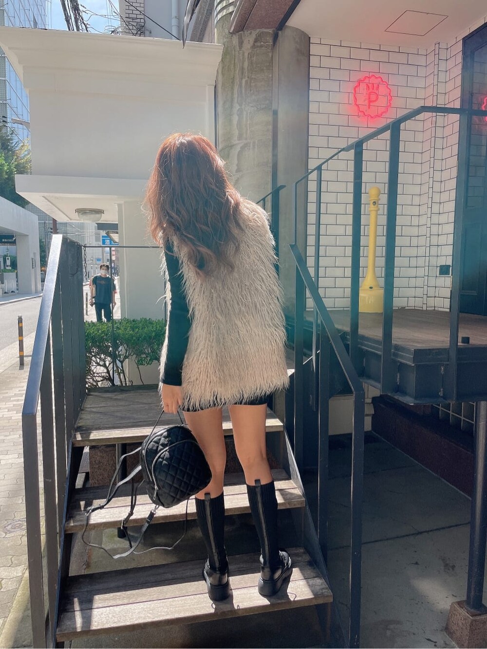 ブラック系のバックパック/リュック、ベージュ系のベスト、ブラック系のブーツを着用したレディースの秋コーディネートの5枚目の写真