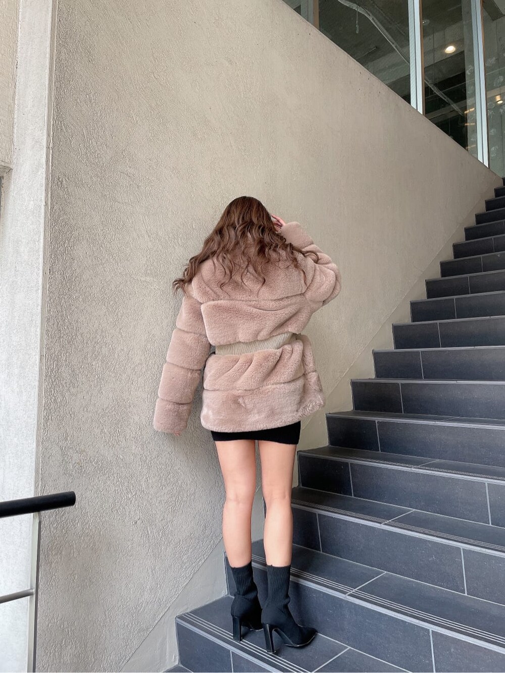 ブラック系のブーツ、ベージュ系のその他アウター、ブラック系のワンピースを着用したレディースの冬コーディネートの3枚目の写真