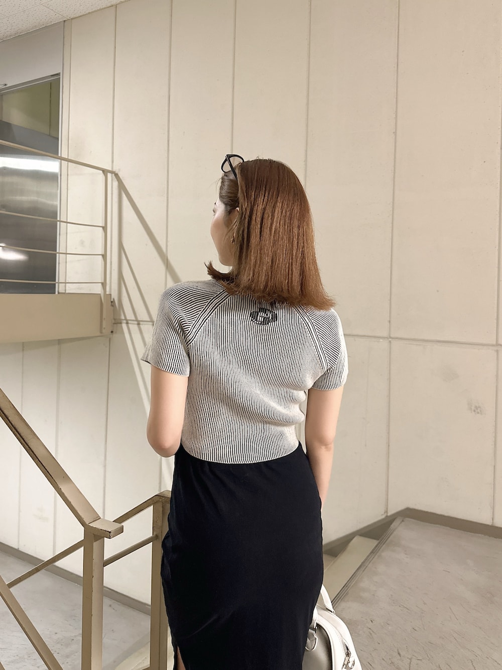 ホワイト系のニット/セーター、ホワイト系のハンドバッグを着用したレディースの夏コーディネートの4枚目の写真