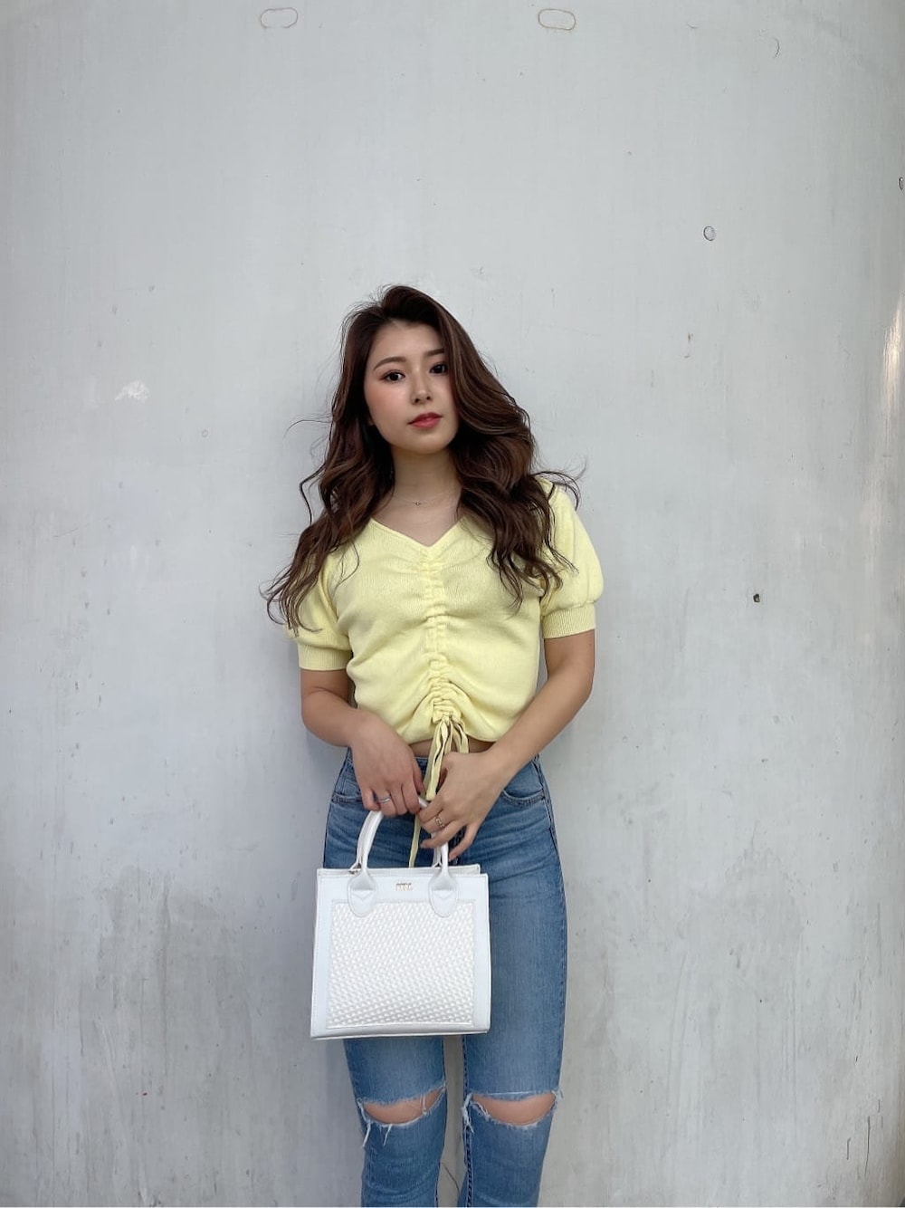 ホワイト系のパンプス、ホワイト系のハンドバッグ、ブルー系のデニムパンツを着用したレディースの春コーディネートの6枚目の写真