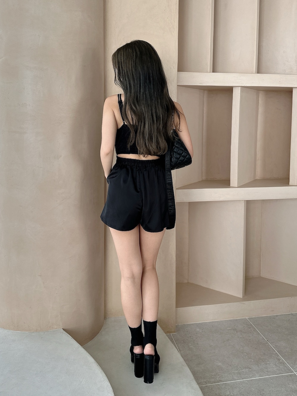 ブラック系のつなぎ/オールインワン、ブラック系のハンドバッグ、ブラック系のブーツを着用したレディースの夏コーディネートの3枚目の写真