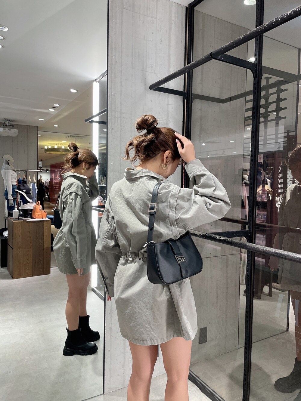 グレー系のミリタリージャケット、ホワイト系のハンドバッグ、ブラック系のブーツを着用したレディースの春コーディネートの7枚目の写真