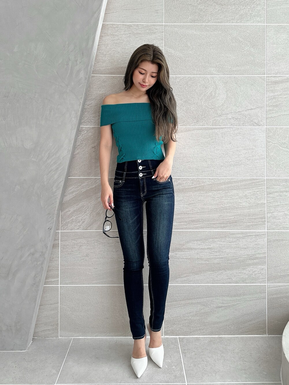 グリーン系のニット/セーター、ホワイト系のパンプス、ブルー系のデニムパンツを着用したレディースの夏コーディネートの2枚目の写真