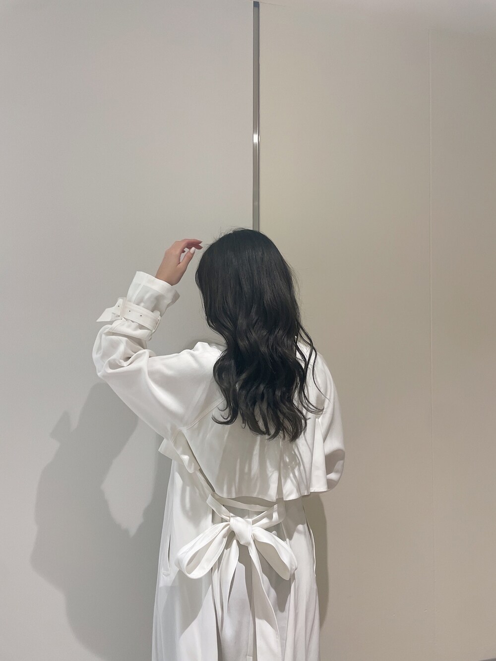 ブルー系のニット/セーター、ホワイト系のトレンチコート、ブルー系のデニムパンツを着用したレディースの春コーディネートの8枚目の写真