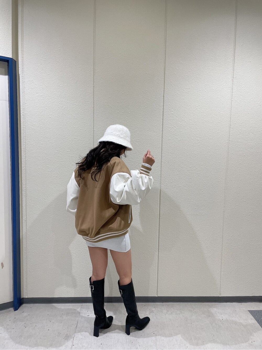 ベージュ系のスタジャン、ブラック系のブーツ、ホワイト系のワンピースを着用したレディースの秋コーディネートの2枚目の写真