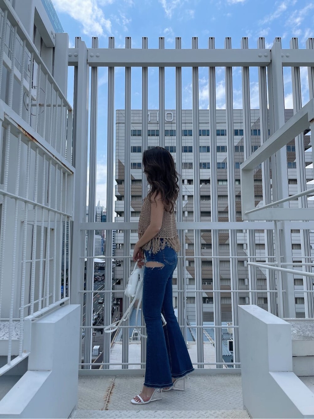 ホワイト系のサンダル、ブルー系のデニムパンツ、ホワイト系のハンドバッグを着用したレディースの夏コーディネートの2枚目の写真