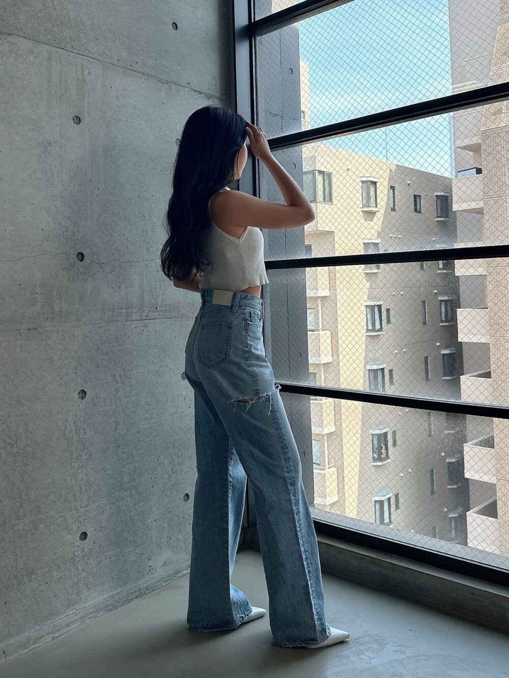 ホワイト系のパンプス、ホワイト系のタンクトップ、ブルー系のデニムパンツを着用したレディースの夏コーディネートの2枚目の写真