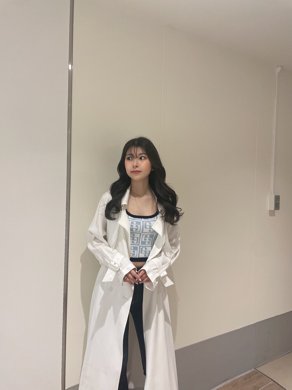 ブルー系のニット/セーター、ホワイト系のトレンチコート、ブルー系のデニムパンツを着用したレディースの春コーディネートの4枚目の写真