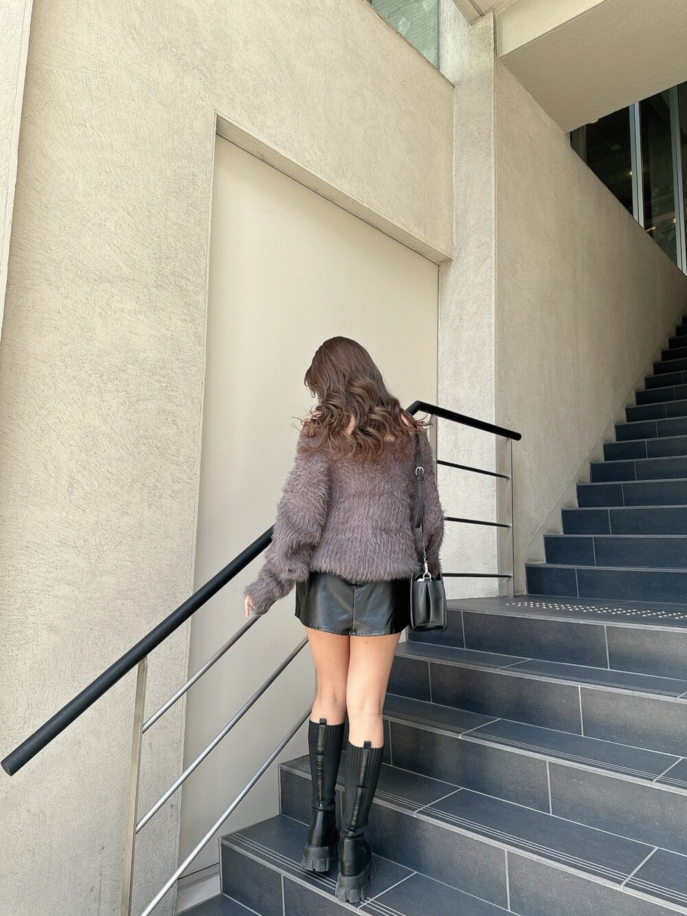 ホワイト系のニット/セーター、ブラック系のスカート、ブラック系のブーツを着用したレディースの冬コーディネートの3枚目の写真