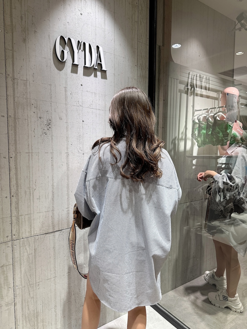 ブルー系のシャツ/ブラウス、ブラック系のスニーカーを着用したレディースの春コーディネートの5枚目の写真