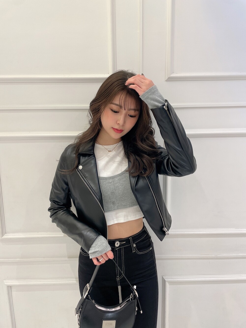 グレー系のTシャツ/カットソー、ブラック系のライダースジャケット、ブラック系のハンドバッグを着用したレディースの冬コーディネートの3枚目の写真