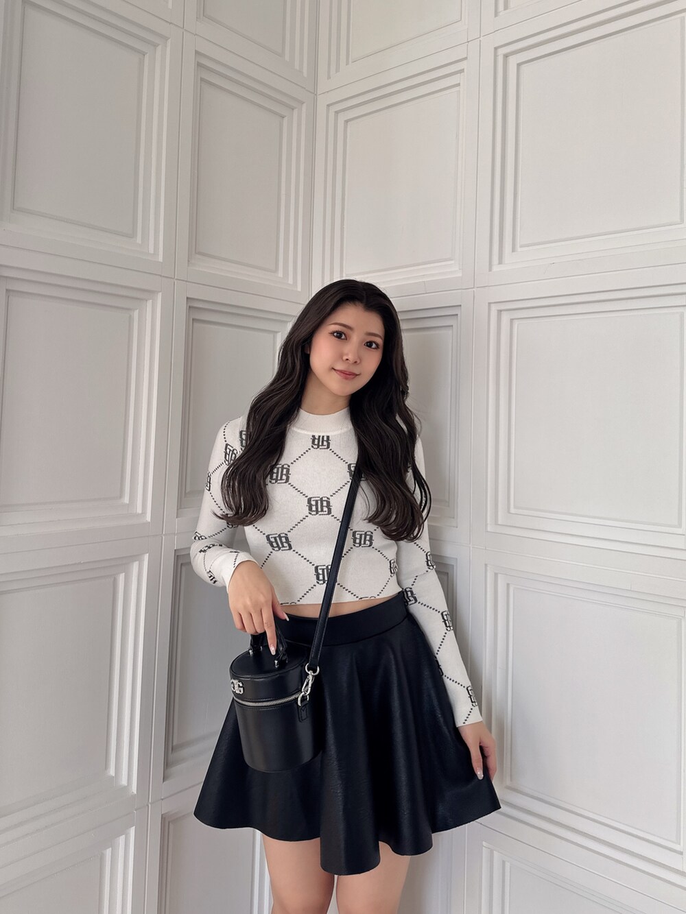 ブラック系のスカート、ブラック系のハンドバッグ、ホワイト系のニット/セーターを着用したレディースの冬コーディネートの5枚目の写真