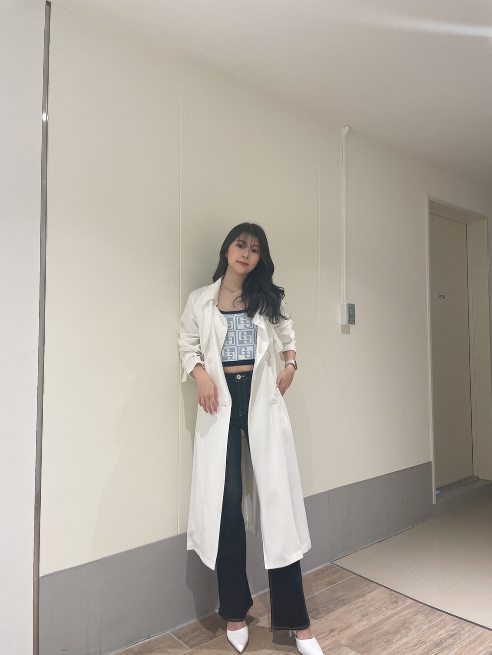 ブルー系のニット/セーター、ホワイト系のトレンチコート、ブルー系のデニムパンツを着用したレディースの春コーディネートの2枚目の写真