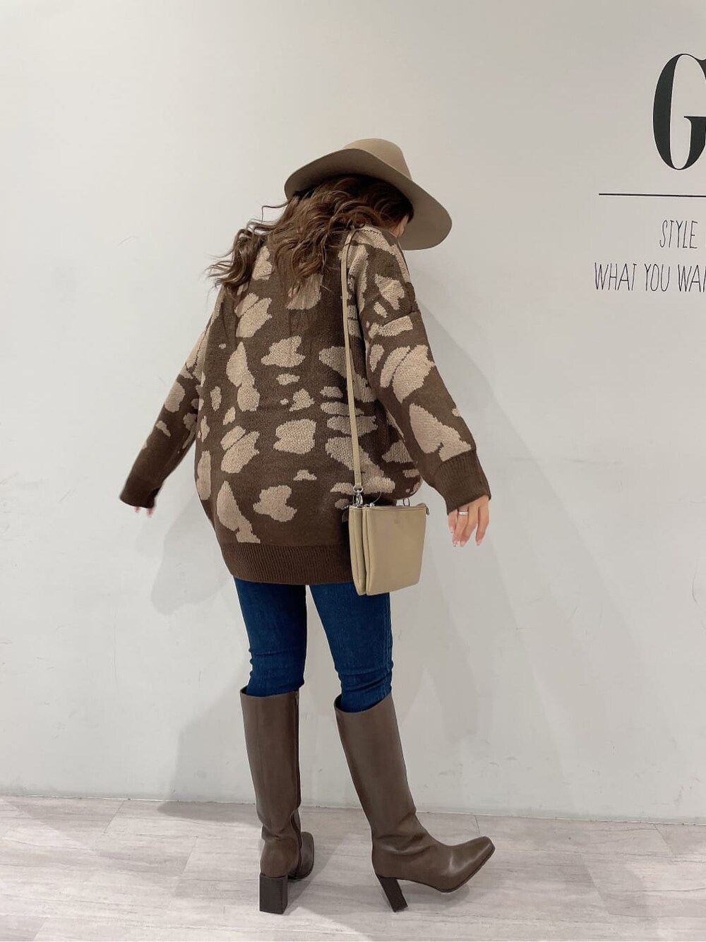 ブラウン系のブーツ、ブルー系のデニムパンツ、ベージュ系のショルダーバッグを着用したレディースの秋コーディネートの3枚目の写真