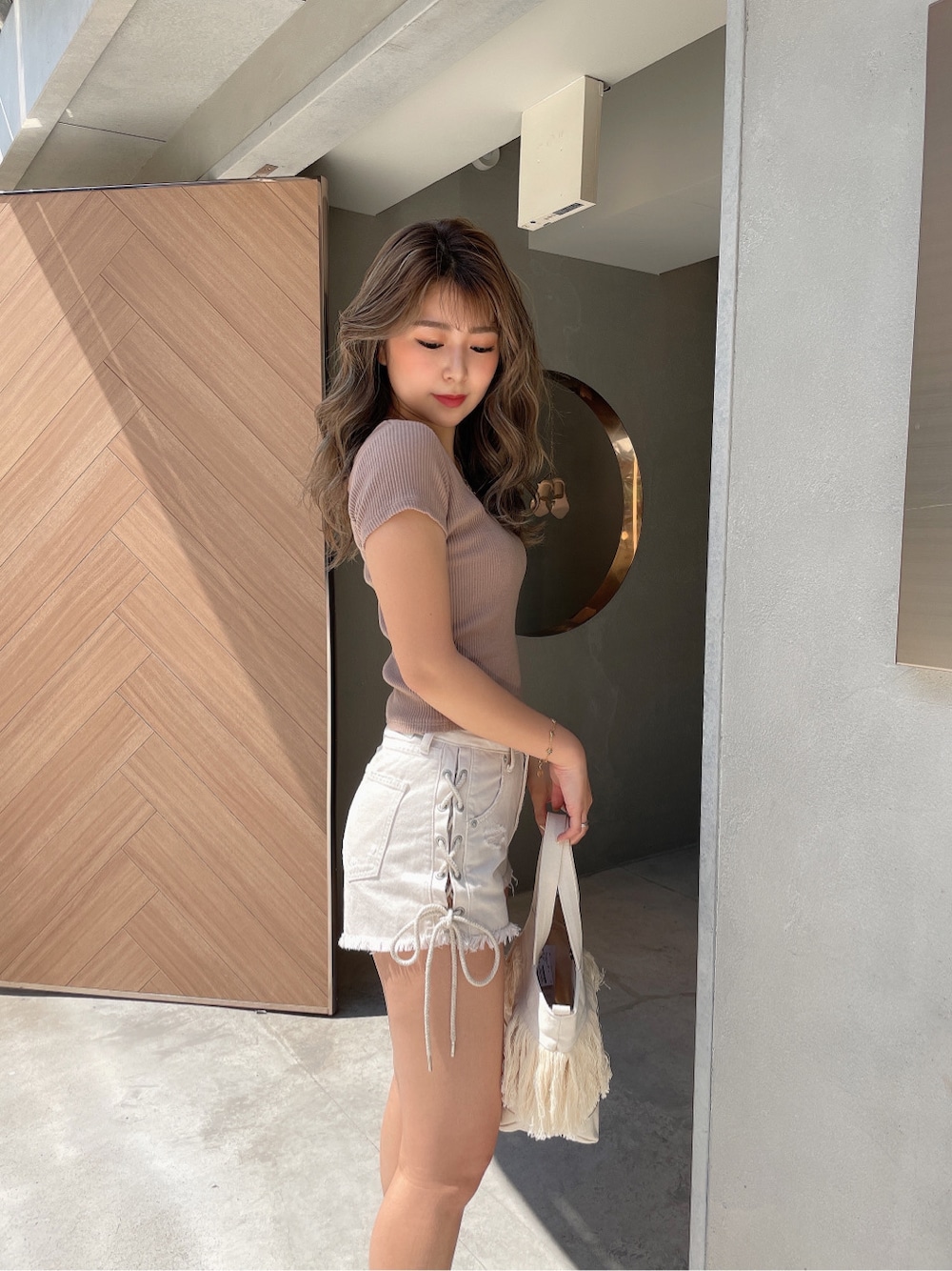 ベージュ系のサンダル、ホワイト系のハンドバッグ、ホワイト系のデニムパンツを着用したレディースの春コーディネートの5枚目の写真