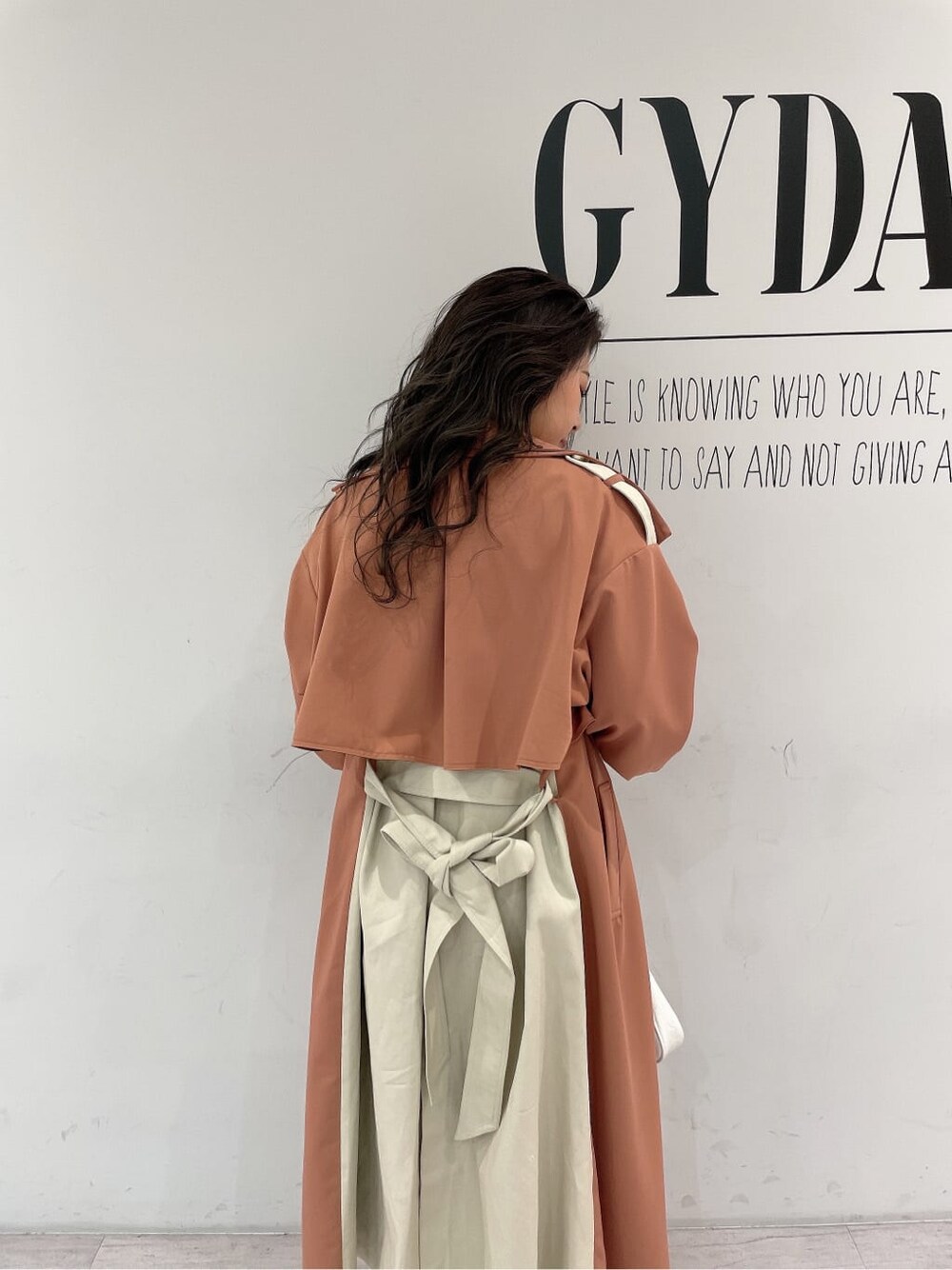 ホワイト系のキャミソール、ホワイト系のパンプス、オレンジ系のトレンチコートを着用したレディースの春コーディネートの6枚目の写真