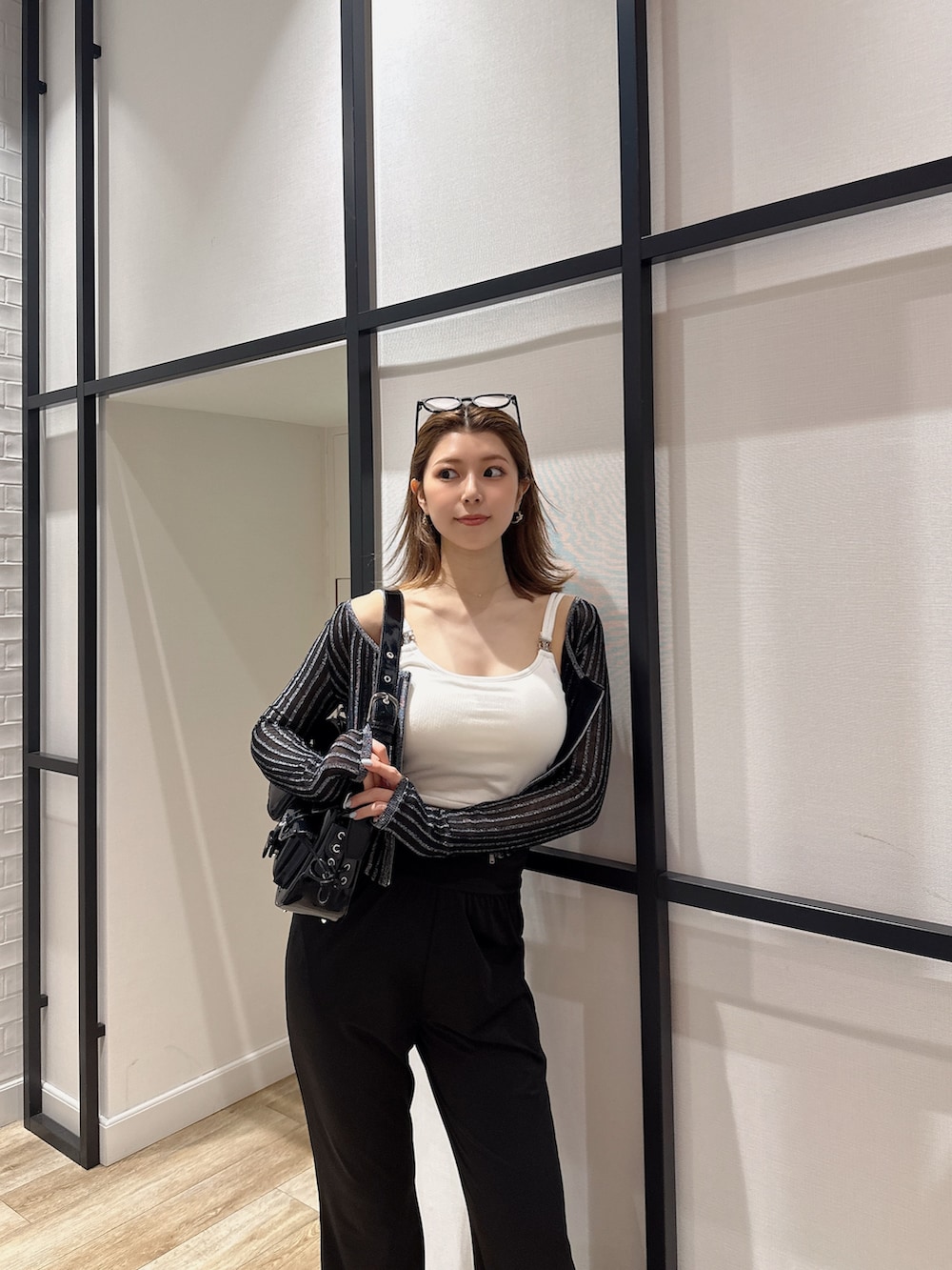 ブラック系のハンドバッグ、ブラック系のカーディガン/ボレロ、ホワイト系のキャミソールを着用したレディースの夏コーディネートの5枚目の写真