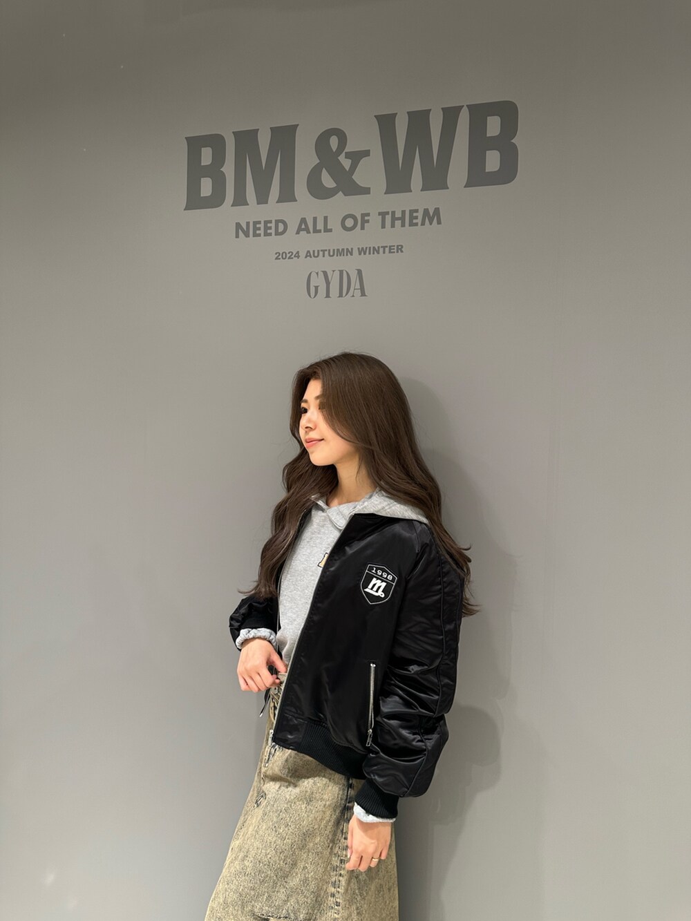 グレー系のパーカー、ブルー系のデニムスカート、ブラック系のブルゾンを着用したレディースの秋コーディネートの4枚目の写真