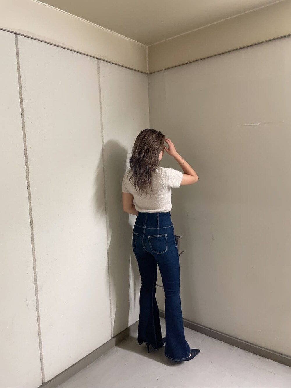 ブラック系のパンプス、ブルー系のデニムパンツ、ベージュ系のショルダーバッグを着用したレディースの夏コーディネートの4枚目の写真