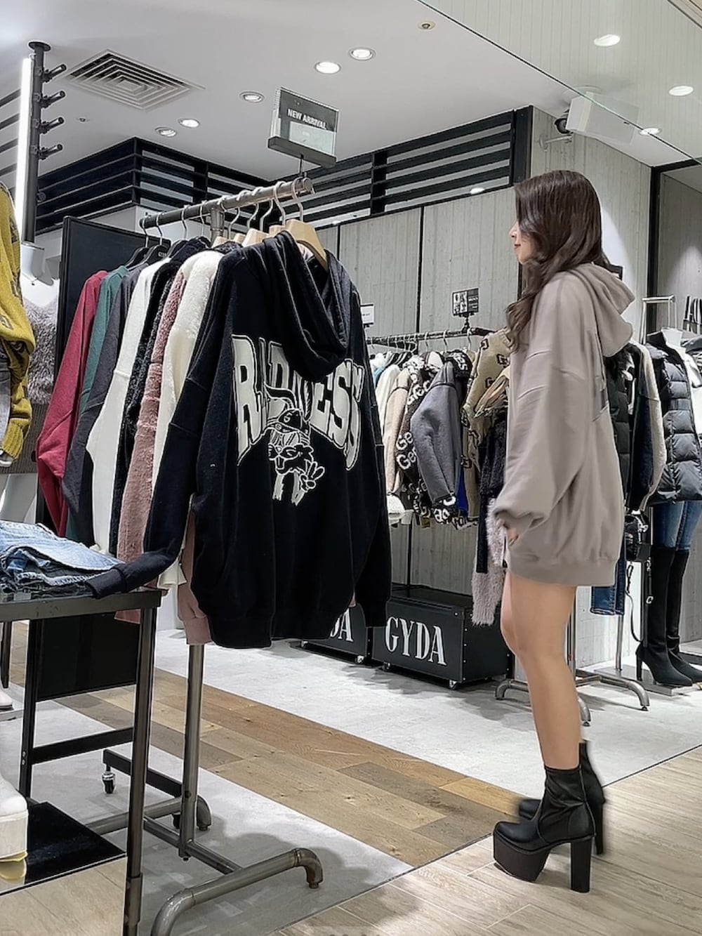 ベージュ系のパーカー、ブラック系のブーツを着用したレディースの秋コーディネートの2枚目の写真