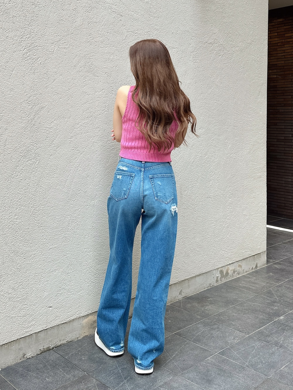 ピンク系のニット/セーター、ブルー系のデニムパンツを着用したレディースの夏コーディネートの2枚目の写真