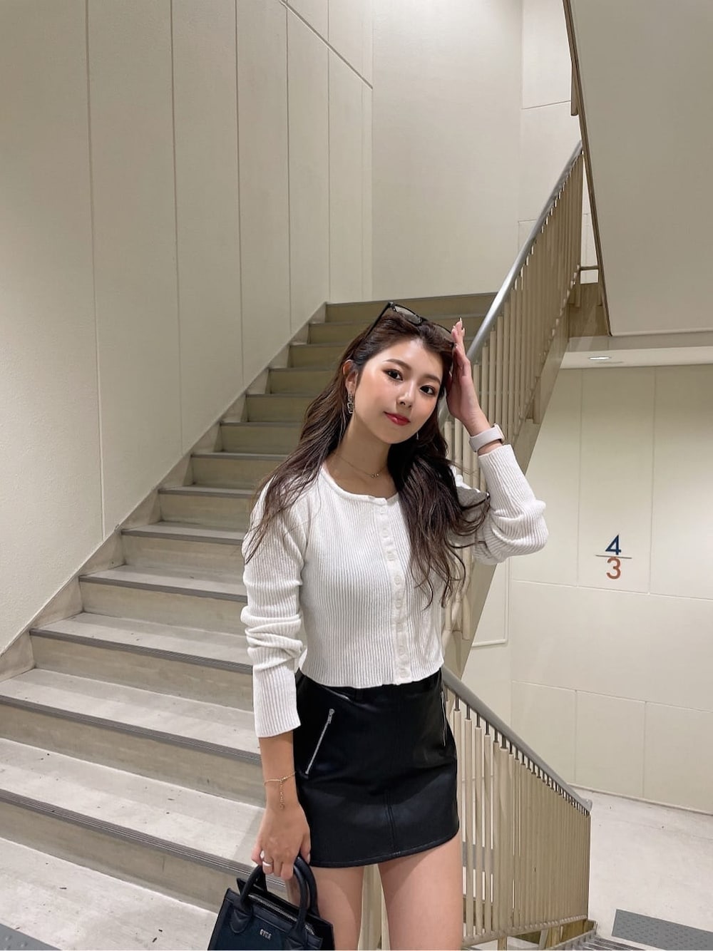 ブラック系のハンドバッグ、ブラック系のスカート、ホワイト系のカーディガン/ボレロを着用したレディースの秋コーディネートの4枚目の写真