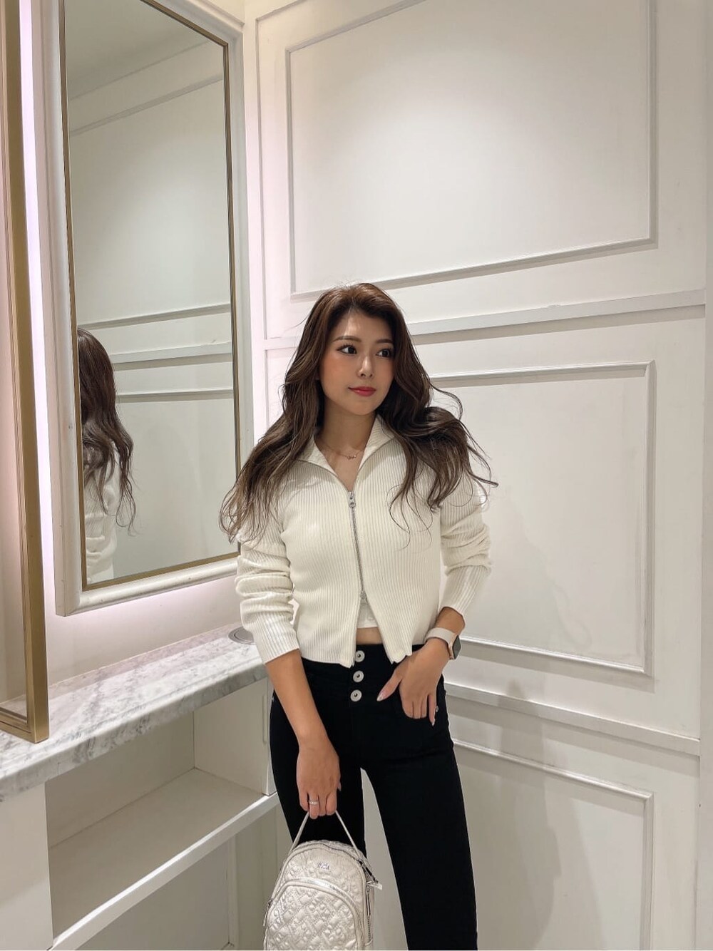 ホワイト系のバックパック/リュック、ホワイト系のニット/セーター、ブラック系のブーツを着用したレディースの秋コーディネートの3枚目の写真