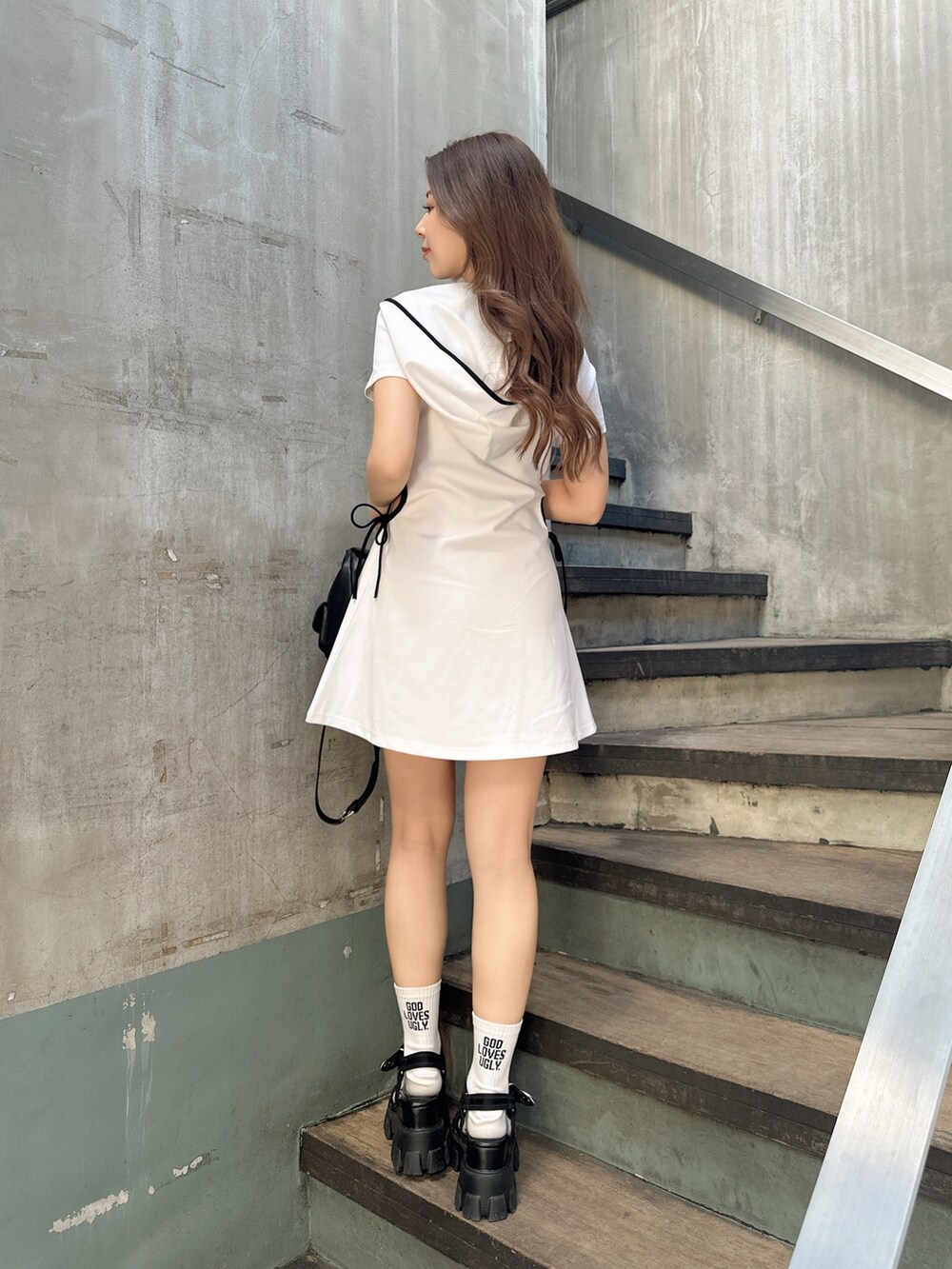 ホワイト系のワンピース、ブラック系のサンダル、ブラック系のバックパック/リュックを着用したレディースの夏コーディネートの3枚目の写真