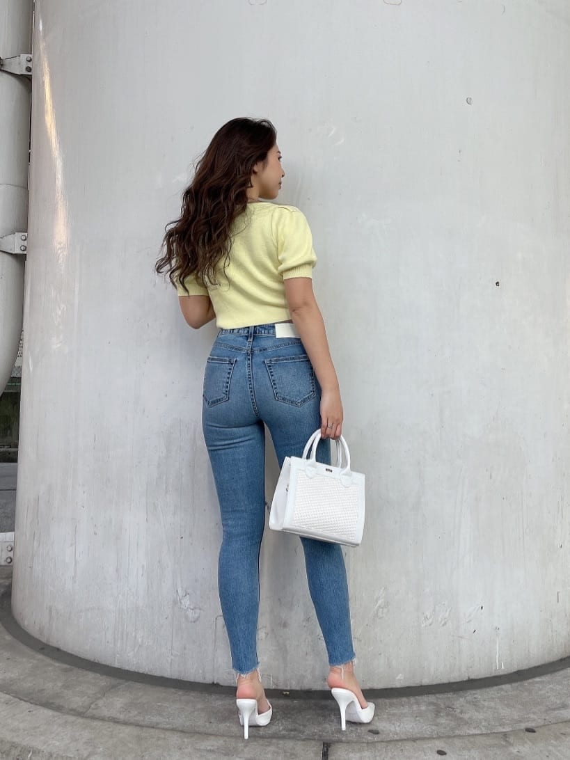 ホワイト系のパンプス、ホワイト系のハンドバッグ、ブルー系のデニムパンツを着用したレディースの春コーディネートの4枚目の写真