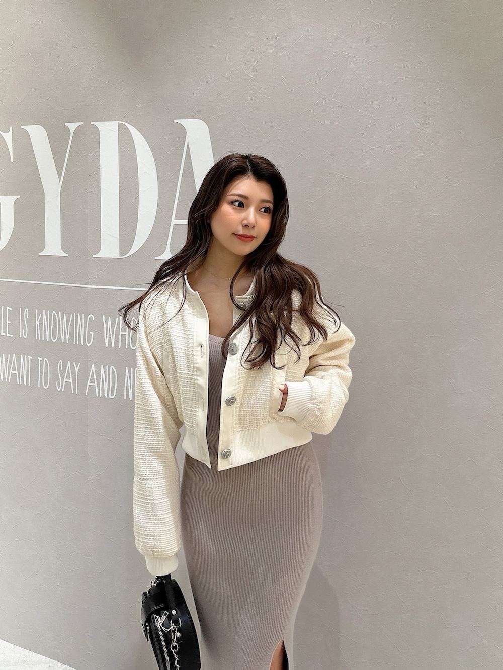 グレー系のワンピース、ホワイト系のブルゾン、ブラック系のハンドバッグを着用したレディースの春コーディネートの5枚目の写真